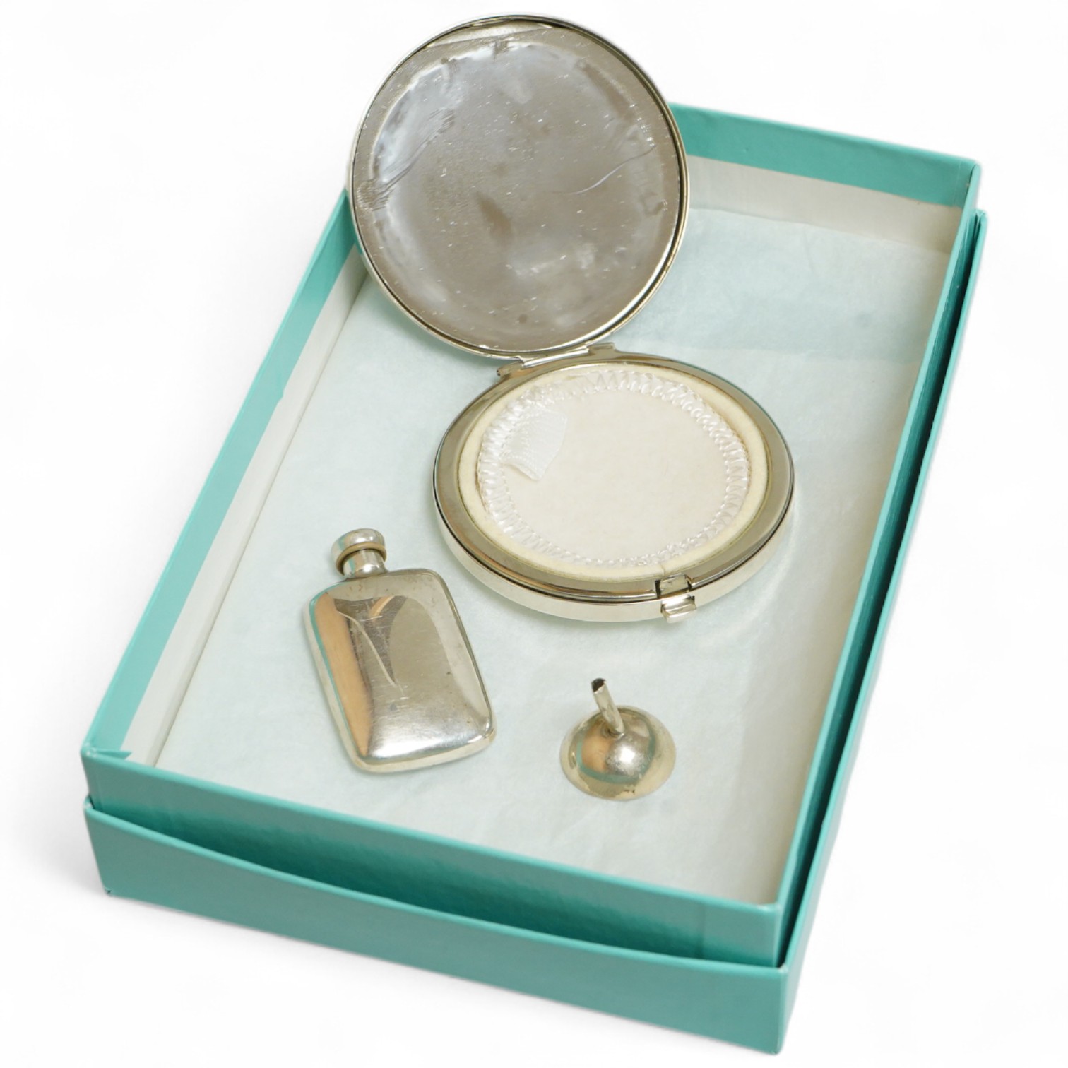 A small modern Tiffany & Co sterling scent flask, 44mm, together with a Tiffany & Co sterling compact, diameter 64mm and a small unmarked white metal funnel, with an associated Tiffany & Co box.